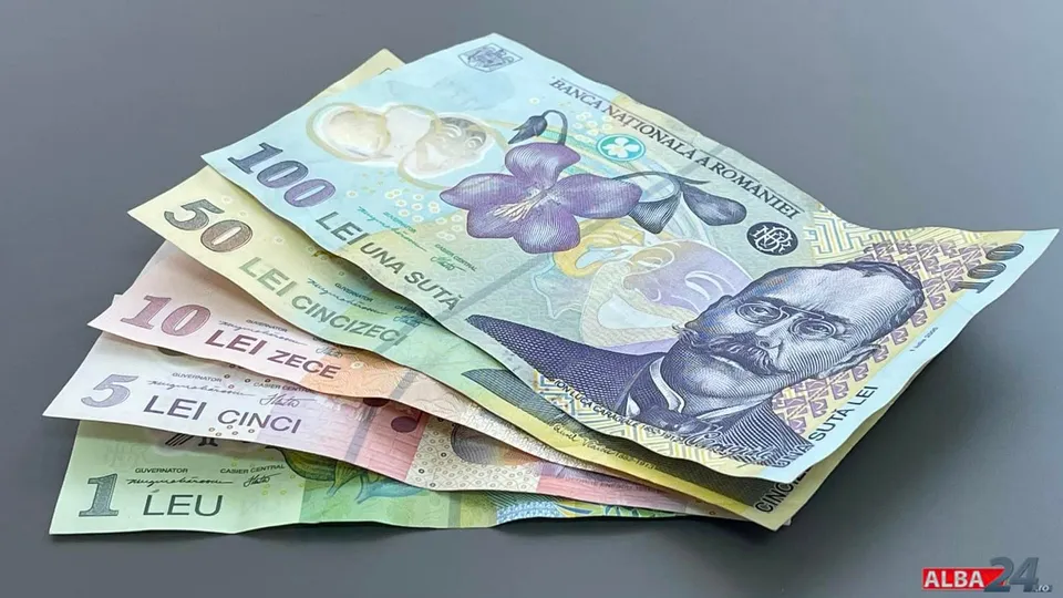 Bancnote românești de 1, 5, 10, 50 și 100 de lei sunt suprapuse pe o suprafață gri.