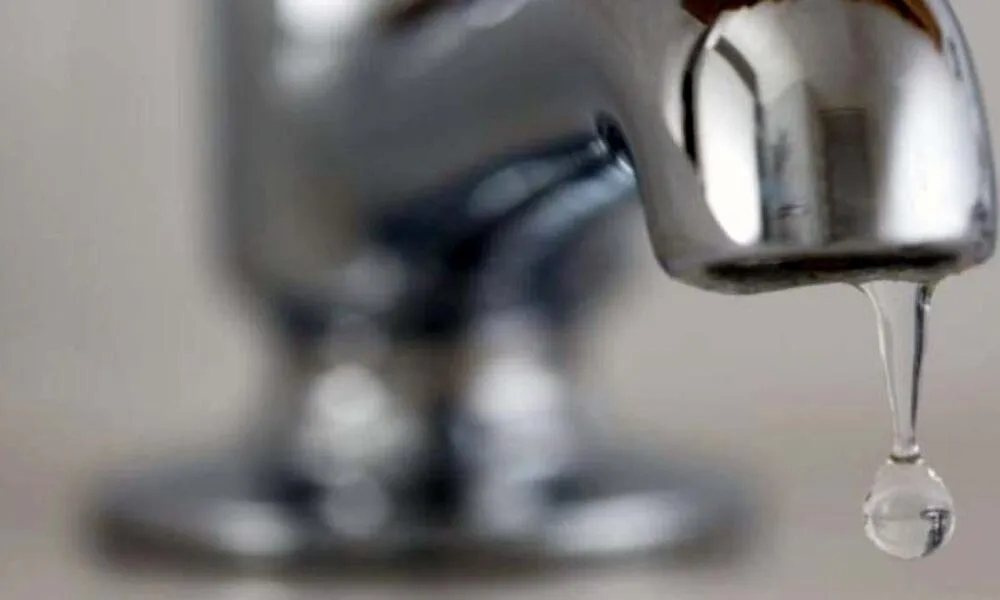 Un robinet metalic lucios, fotografiat de aproape, lasă să cadă o picătură de apă.