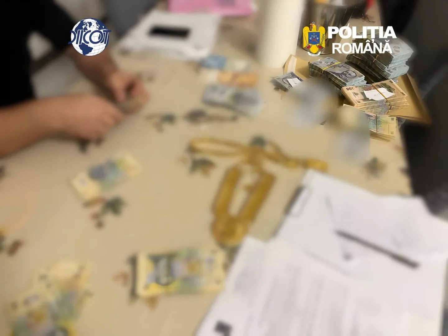 Pe o masă se văd bancnote, plicuri și foi tipărite; în stânga apar mâinile unei persoane, iar în colțurile de sus sunt sigle.