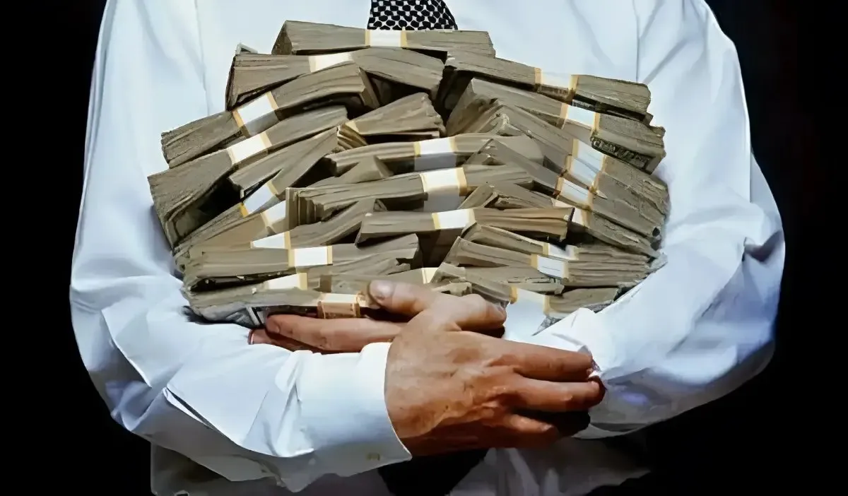 O persoană îmbrăcată într-o cămașă albă ține în brațe numeroase teancuri de bancnote.