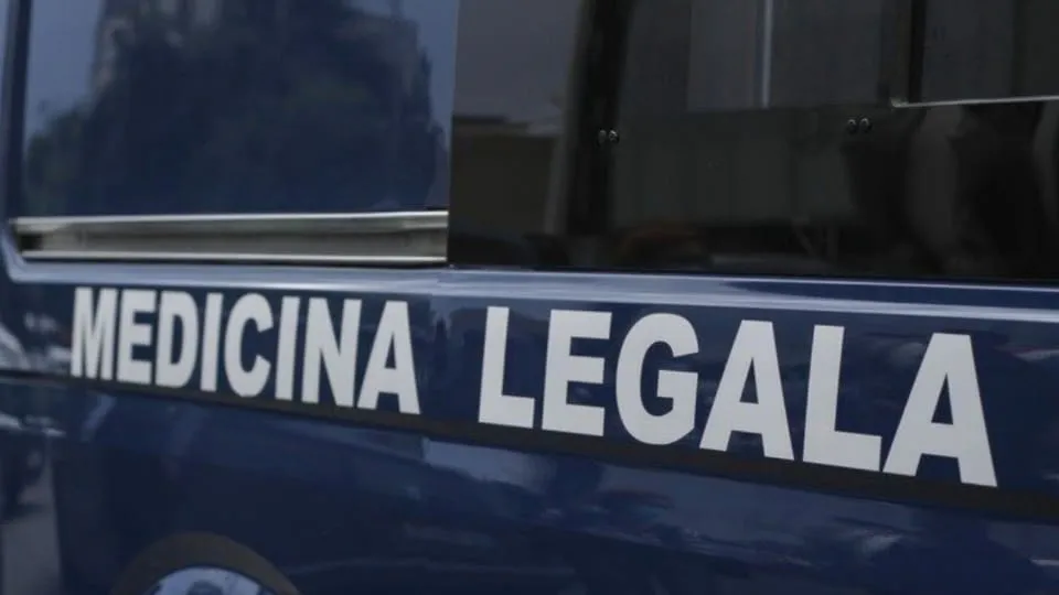 Un vehicul albastru închis ocupă cadrul, cu inscripția albă „MEDICINA LEGALĂ” pe lateral și geamuri întunecate în partea superioară.