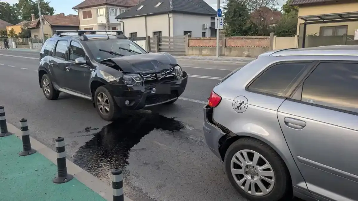 Un SUV negru se află lângă un autoturism argintiu, cu avarii vizibile, iar pe carosabil se vede o pată întunecată.