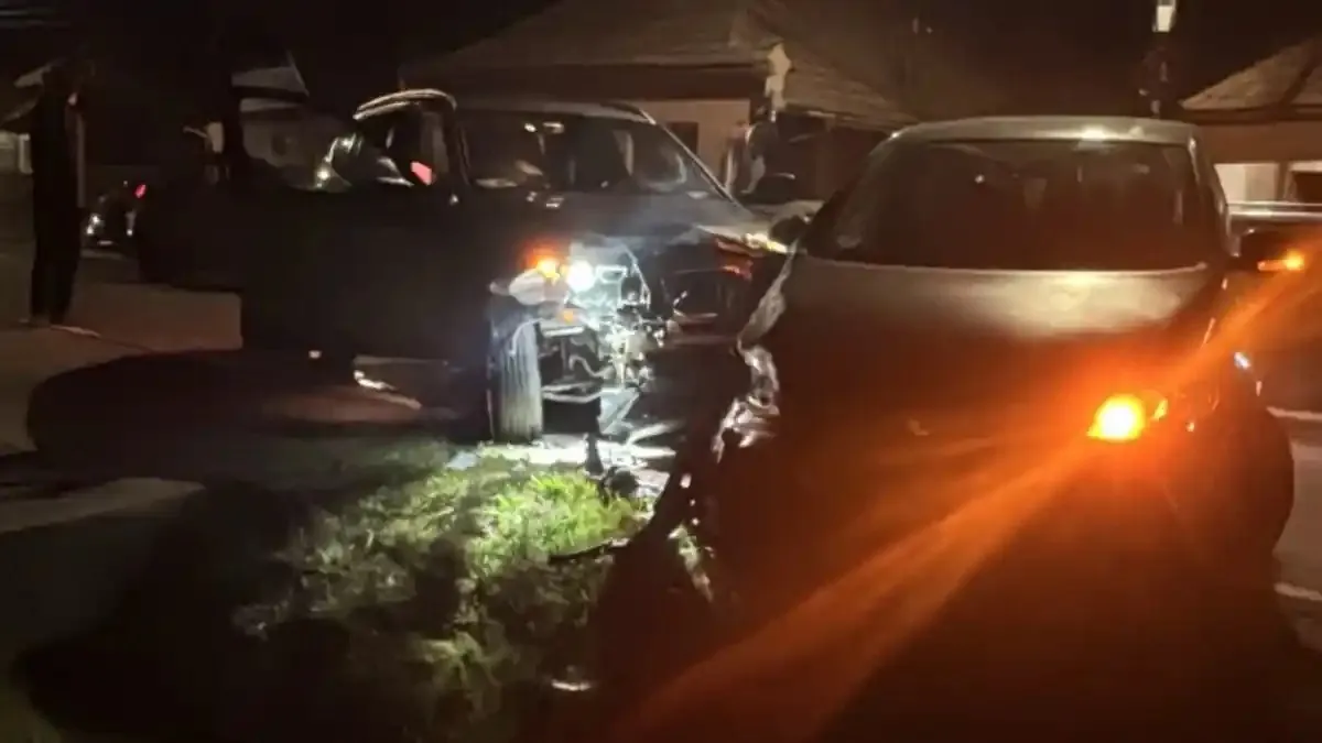 Două autoturisme sunt oprite noaptea, unul cu portiera deschisă și farurile aprinse, iar celălalt are luminile din față aprinse.