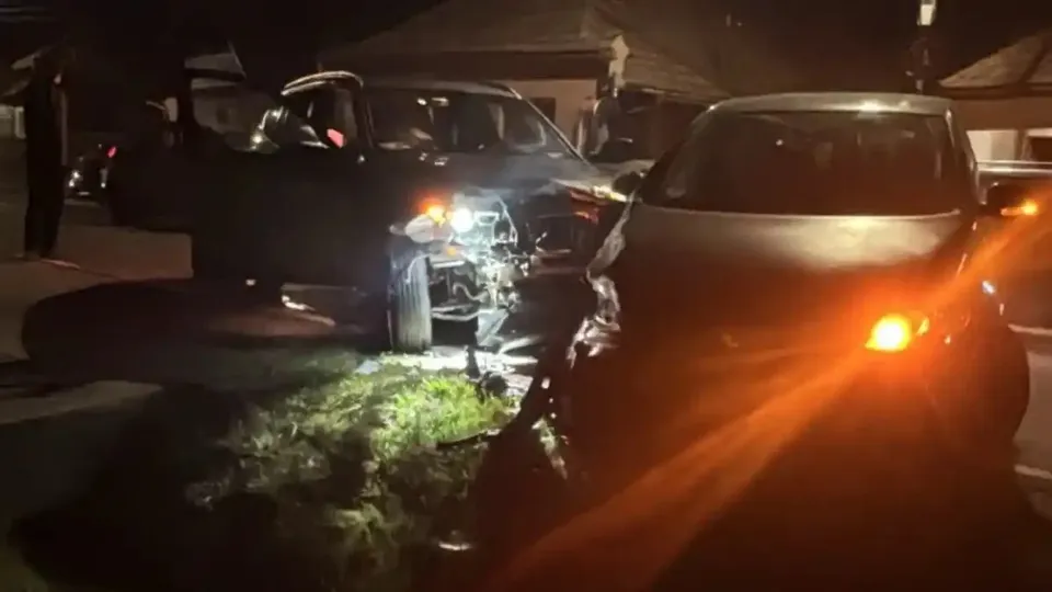 Două autoturisme sunt oprite noaptea, unul cu portiera deschisă și farurile aprinse, iar celălalt are luminile din față aprinse.