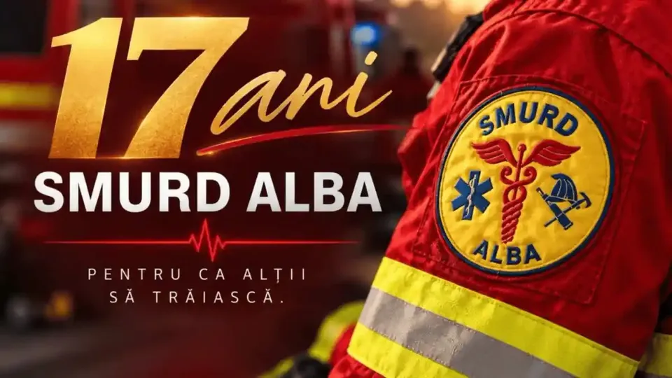 În prim-plan se vede mâneca unei uniforme roșii, cu ecuson circular și bandă reflectorizantă; în fundal apare textul «17 ani SMURD ALBA».