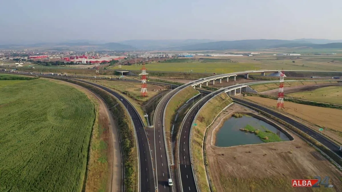 O imagine aeriană arată șosele curbe și pasaje, câmpuri verzi și maronii, un bazin cu apă și stâlpi metalici.