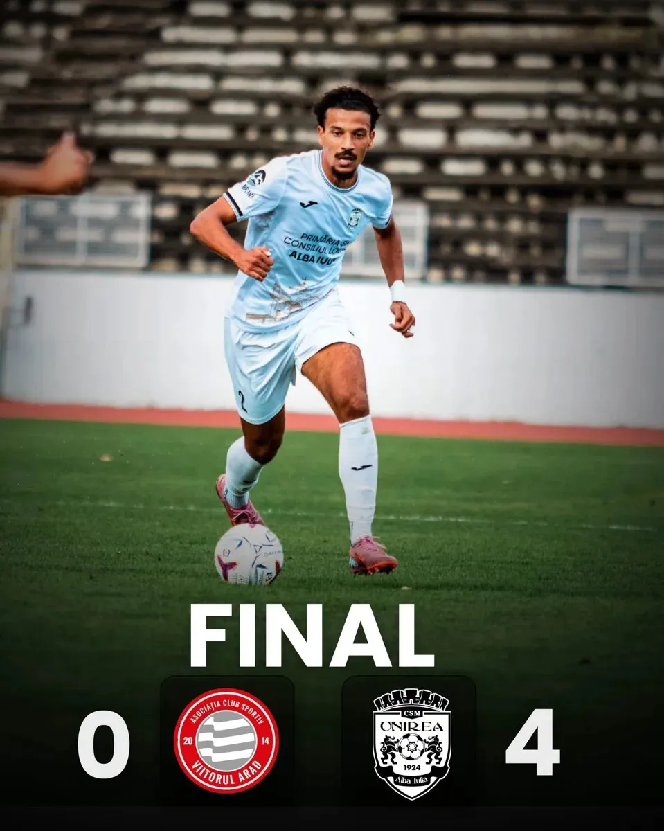Un fotbalist în echipament bleu aleargă cu mingea pe gazon, în fața tribunelor, deasupra unui grafic cu scorul final 0–4.