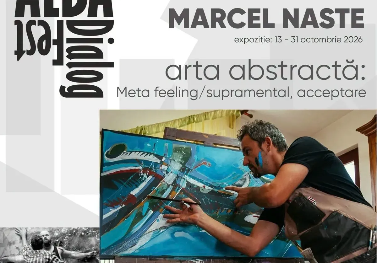 Un bărbat în tricou negru se apleacă spre o pânză mare, ținând o pensulă lângă suprafața pictată în albastru și turcoaz.