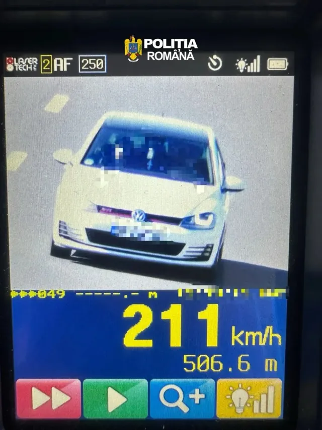 Ecranul unui aparat afișează frontal un autoturism alb, sigla Poliției Române și viteza de 211 km/h.