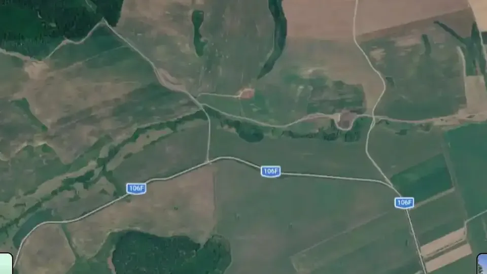 Imagine satelitară cu terenuri agricole, zone împădurite, drumuri și trei marcaje albastre cu inscripția 106F.