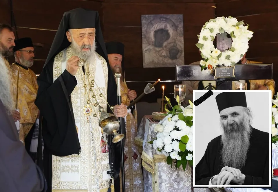 Mai mulți clerici în veșminte religioase stau lângă o cruce cu flori albe, lumânări și un portret alb-negru suprapus.