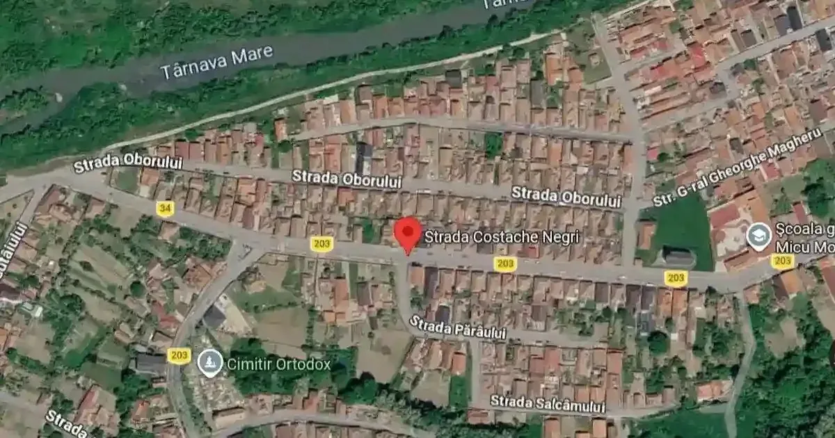 Imagine aeriană cu numeroase clădiri, străzi, vegetație și o fâșie de apă în partea superioară.