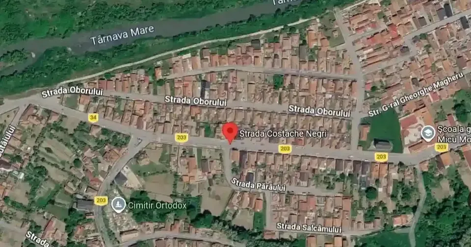 Imagine aeriană cu numeroase clădiri, străzi, vegetație și o fâșie de apă în partea superioară.